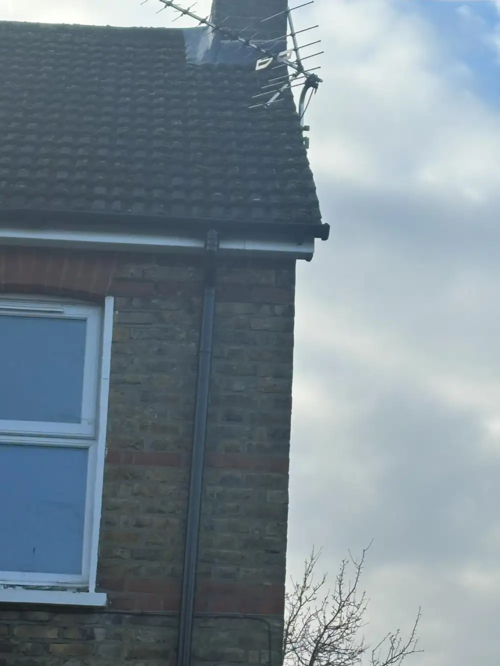Gable end of a brick house showing the roofline and guttering