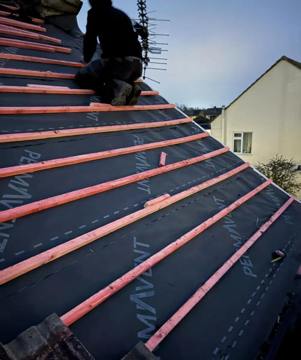 Roofer fixing new battens over breathable membrane on a new roof