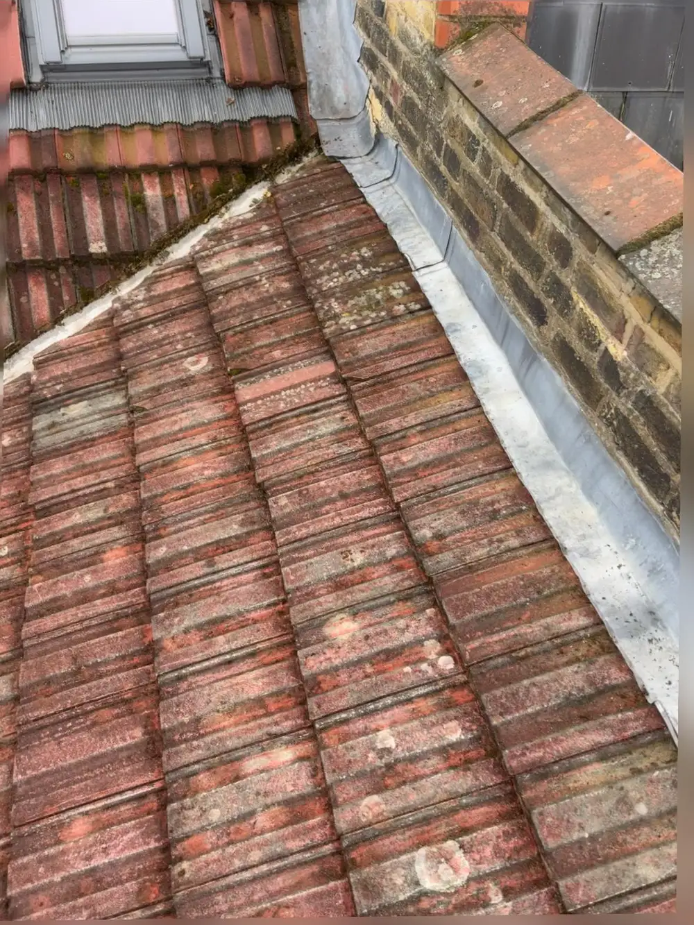 Red tiled roof with a lead abutment flashing against brickwork