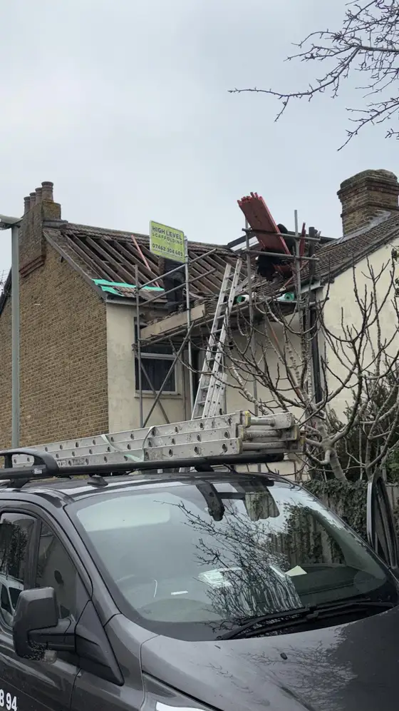 House under scaffolding with the old roof stripped off