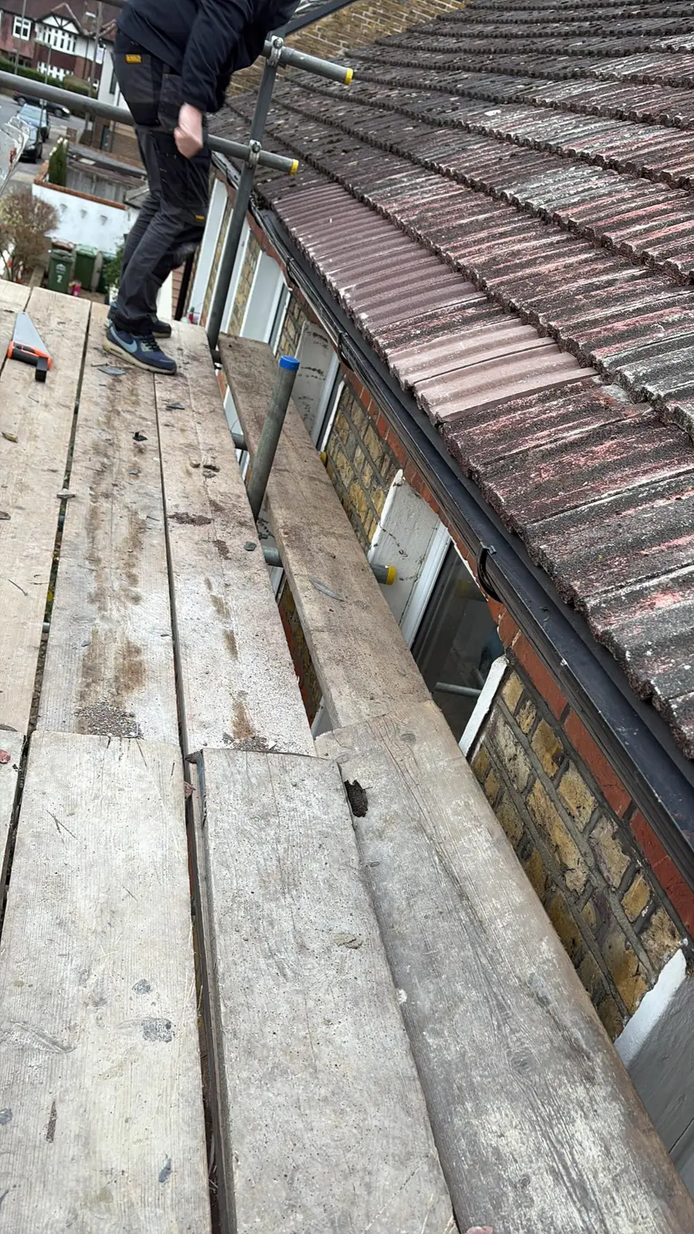 Scaffold walkway running along the eaves of a tiled roof